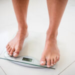 Feet of woman on weighting scale at home