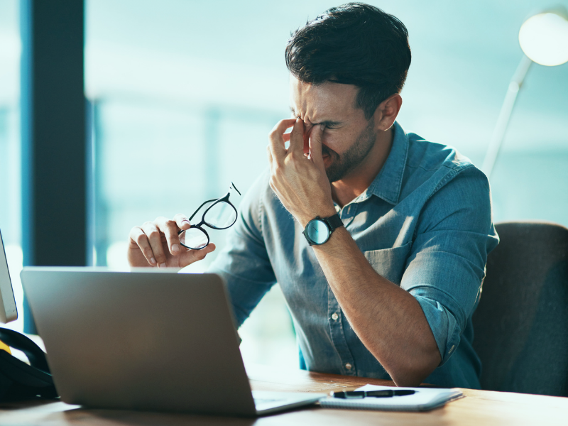 Homem estressado no trabalho em frente ao computador coçando os olhos - ansiedade e estresse